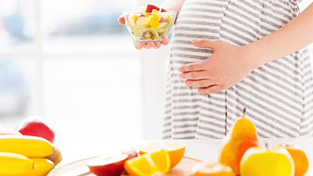 Pregnant woman holding bowl of fruit